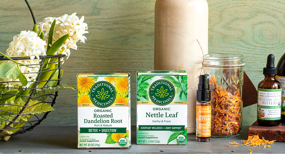 Two Traditional Medicinals tea boxes along with tincture bottles and flowers on shelf