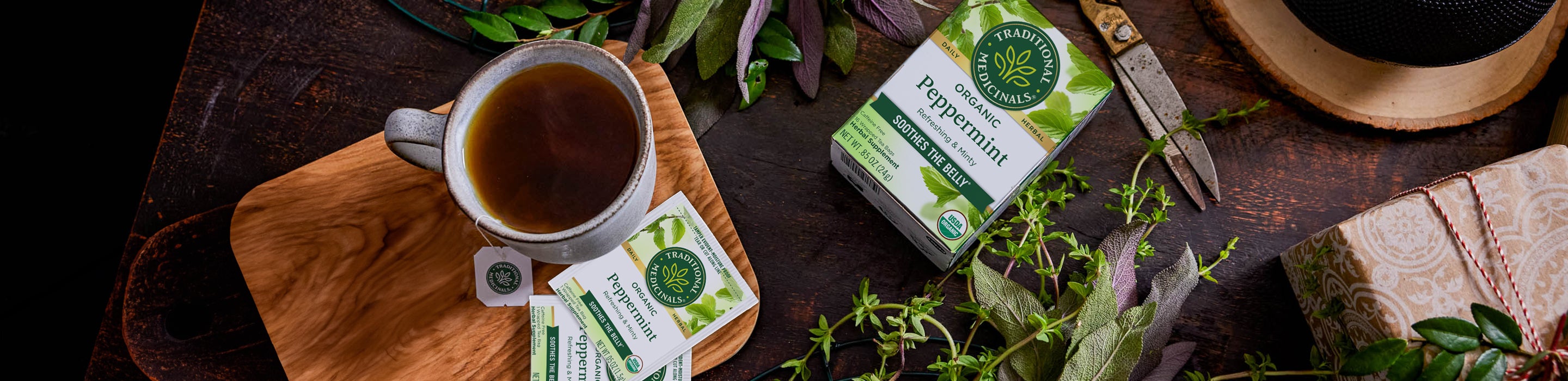 Peppermint tea next to fresh peppermint leaves and steeping mug