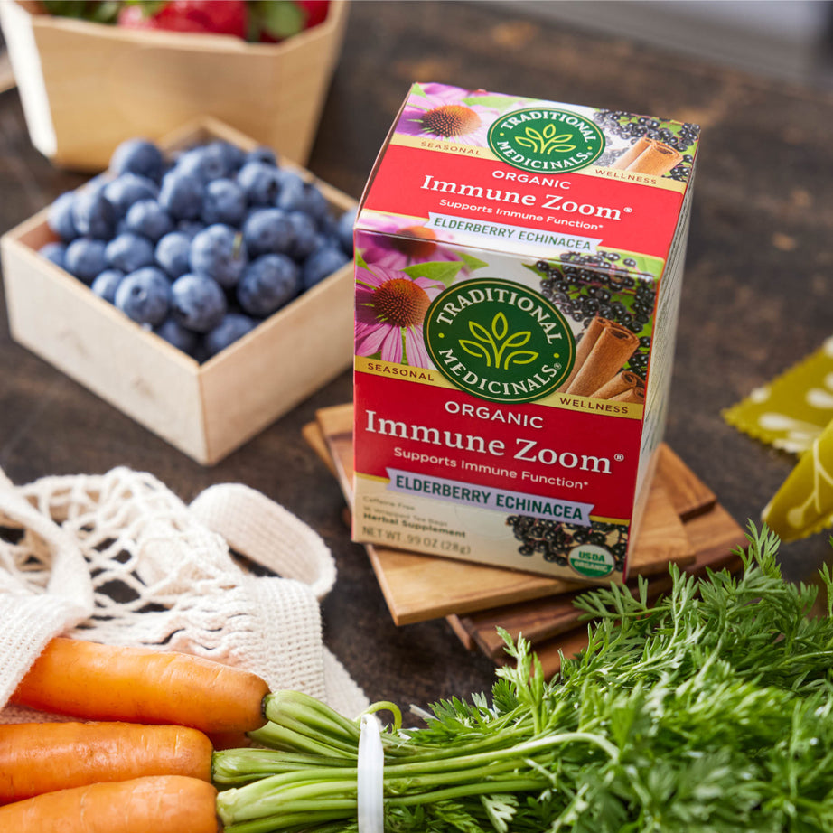 A box of Immune Zoom® Elderberry Echinacea Tea sits gracefully on a wooden table, offering a soothing blend that promotes immune support.