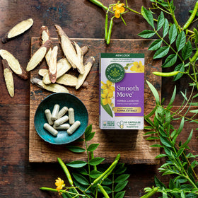 A box of Smooth Move® Capsules, providing natural constipation relief with senna-based herbs and leaves, is elegantly displayed on a wooden surface.